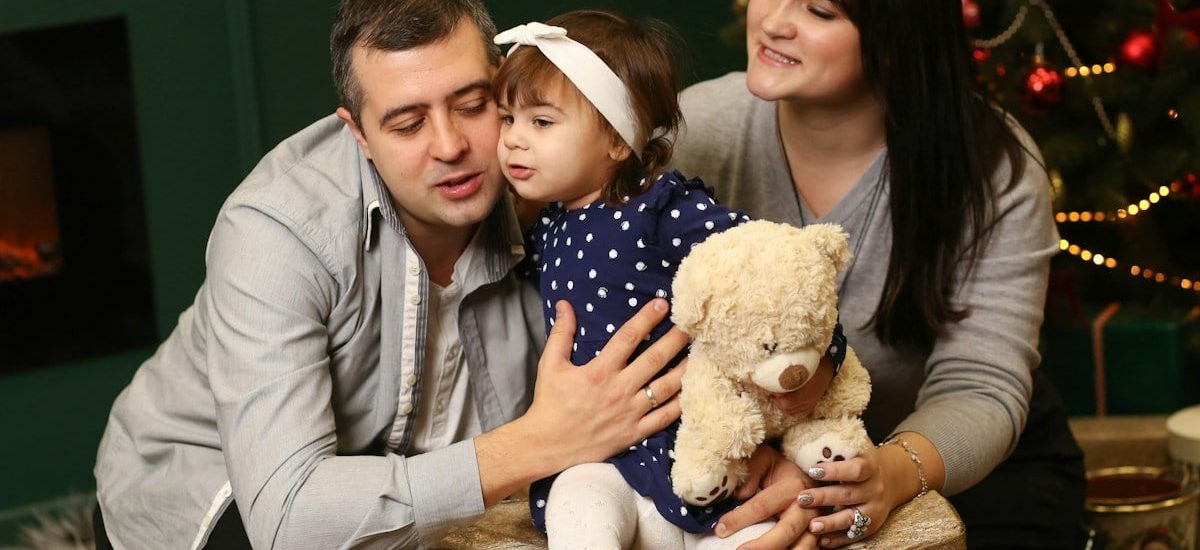 a man, woman and child sitting in front of a christmas tree