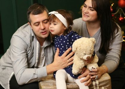 a man, woman and child sitting in front of a christmas tree